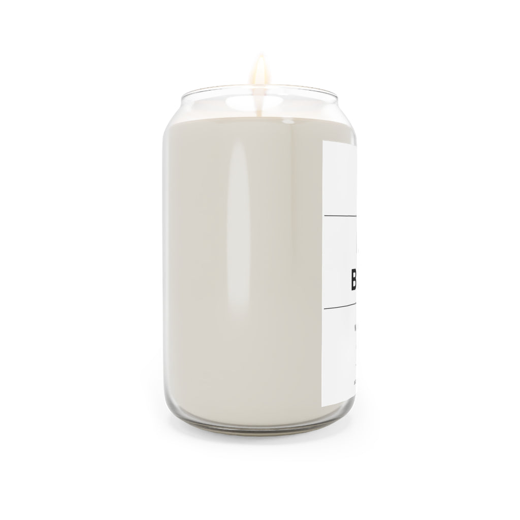 Soy candle in clear jar with flame, off-white wax, label partially visible
