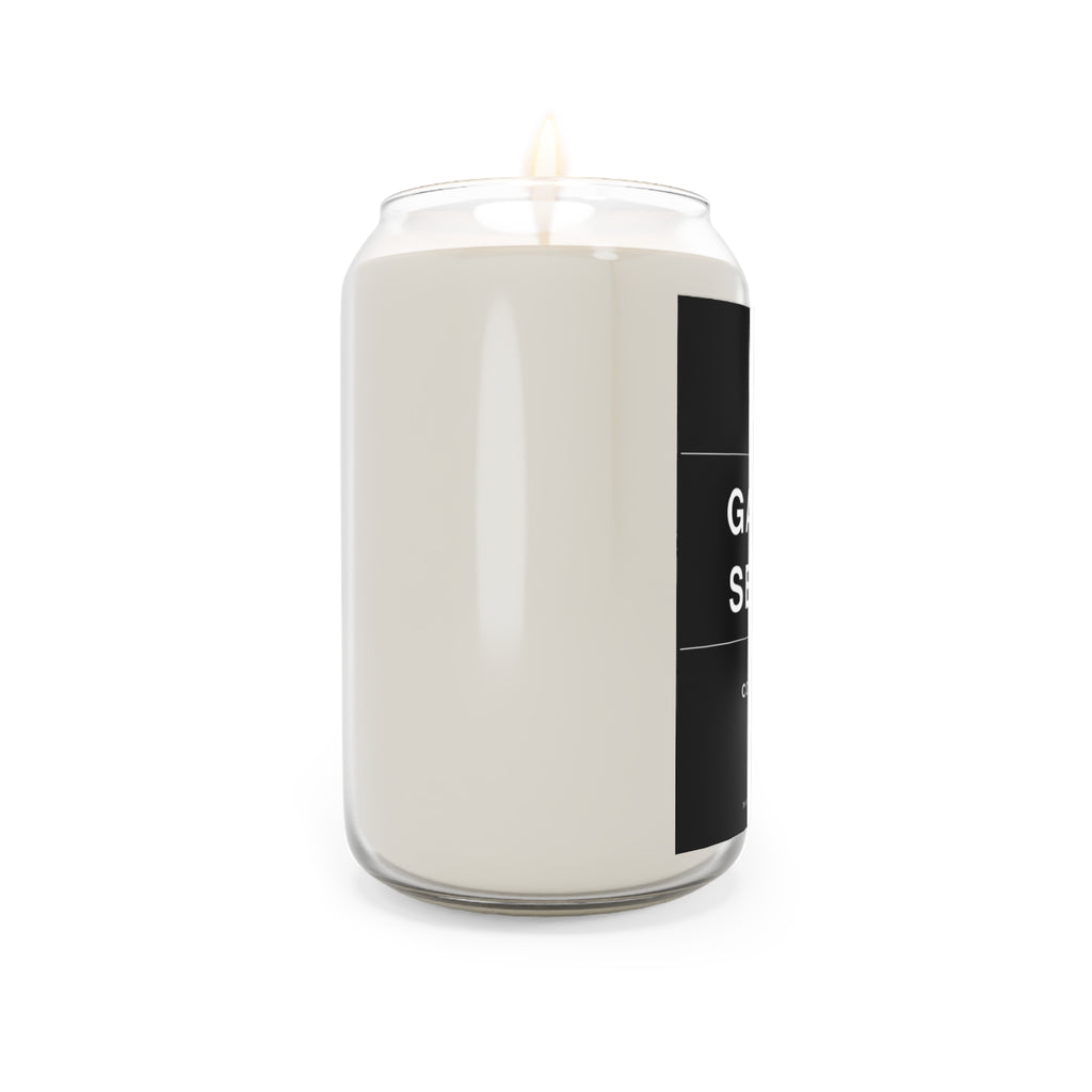 Off-white soy candle in clear glass jar with black side label and burning wick