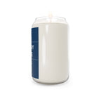 Soy candle in clear glass jar with blue label stripe and lit wick flame visible
