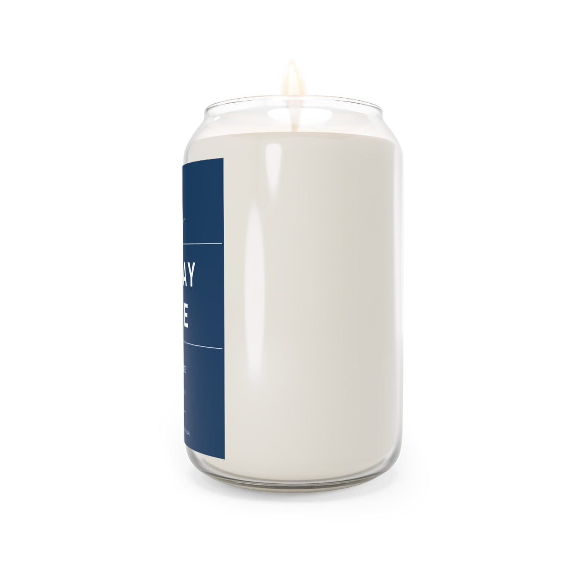 Soy candle in clear glass jar with blue label stripe and lit wick flame visible