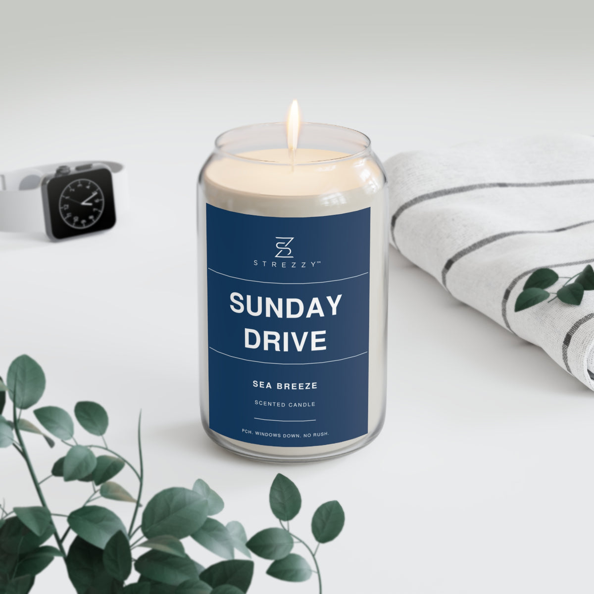 Soy candle in clear glass jar with blue label and lit wick flame
