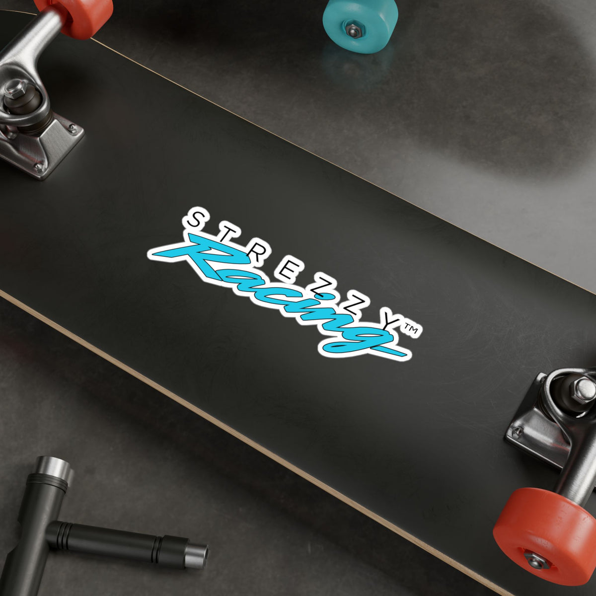 Kiss-cut racing logo sticker centered on skateboard deck, teal “Kaching” script