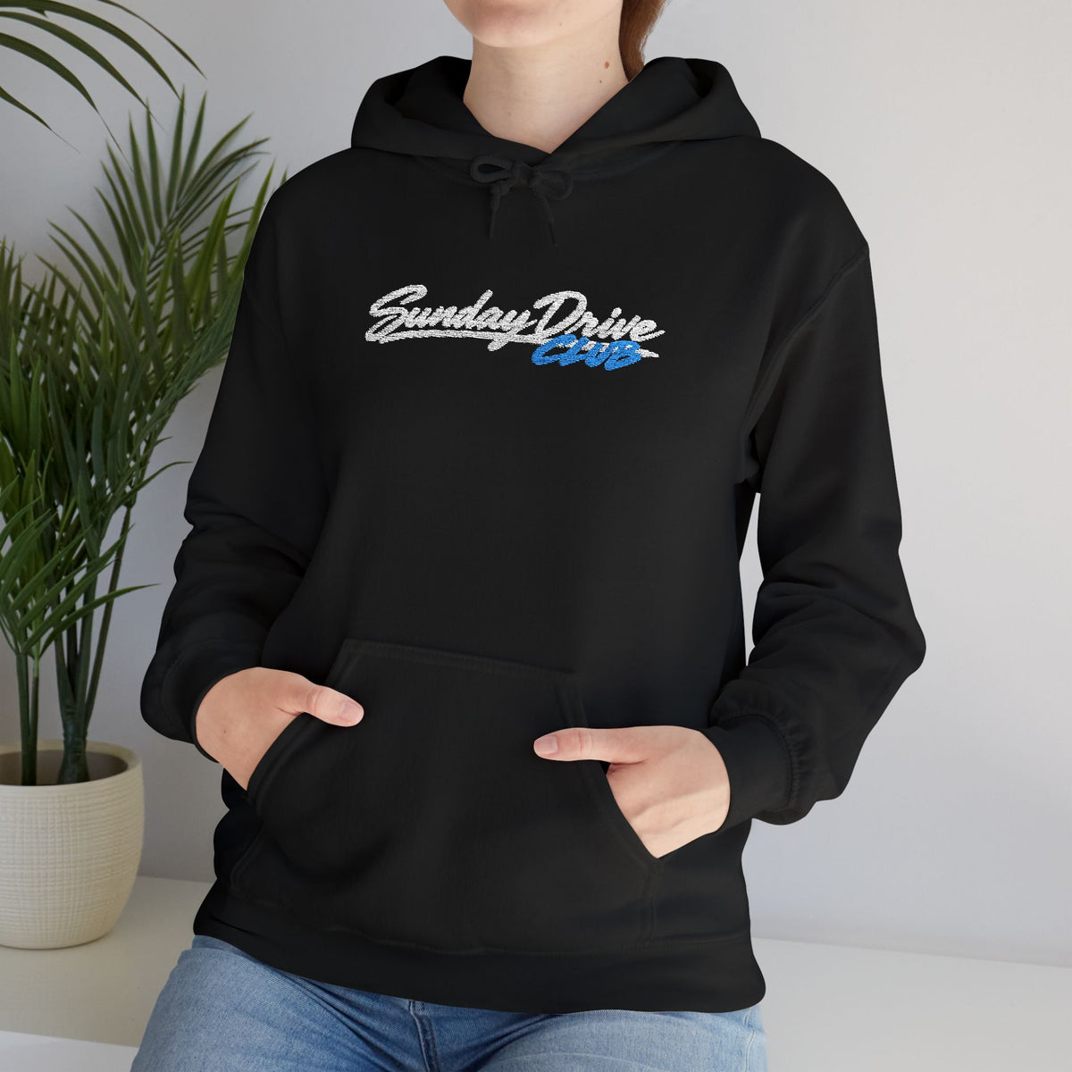 Black pullover hoodie worn by model, embroidered chest logo and kangaroo pocket