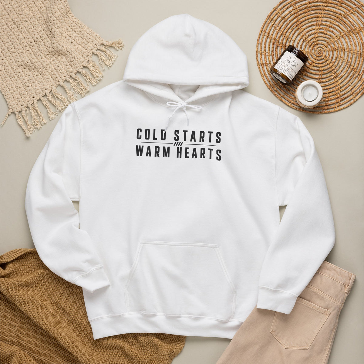 White hoodie with drawstring hood, front pocket, and “COLD STARTS WARM HEARTS” text.