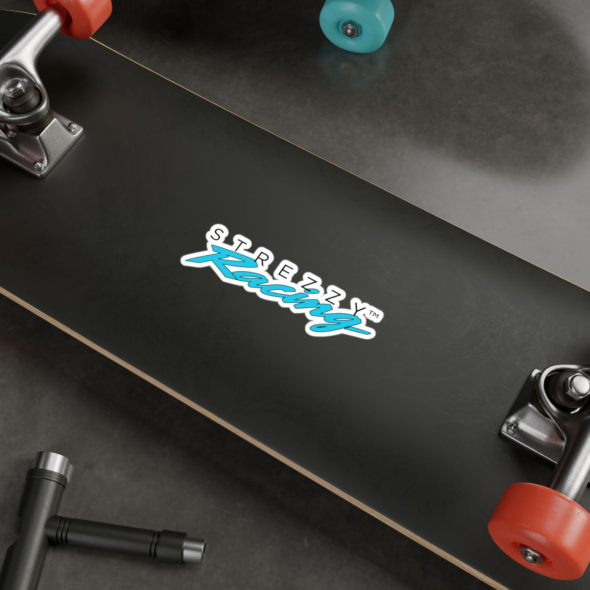 Kiss-cut racing logo sticker on skateboard deck with “STREZZY” and teal “Kaching”