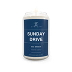 Soy candle in clear glass jar with blue Sunday Drive label and lit wick flame