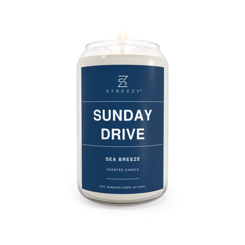 Soy candle in clear glass jar with blue Sunday Drive label and lit wick flame