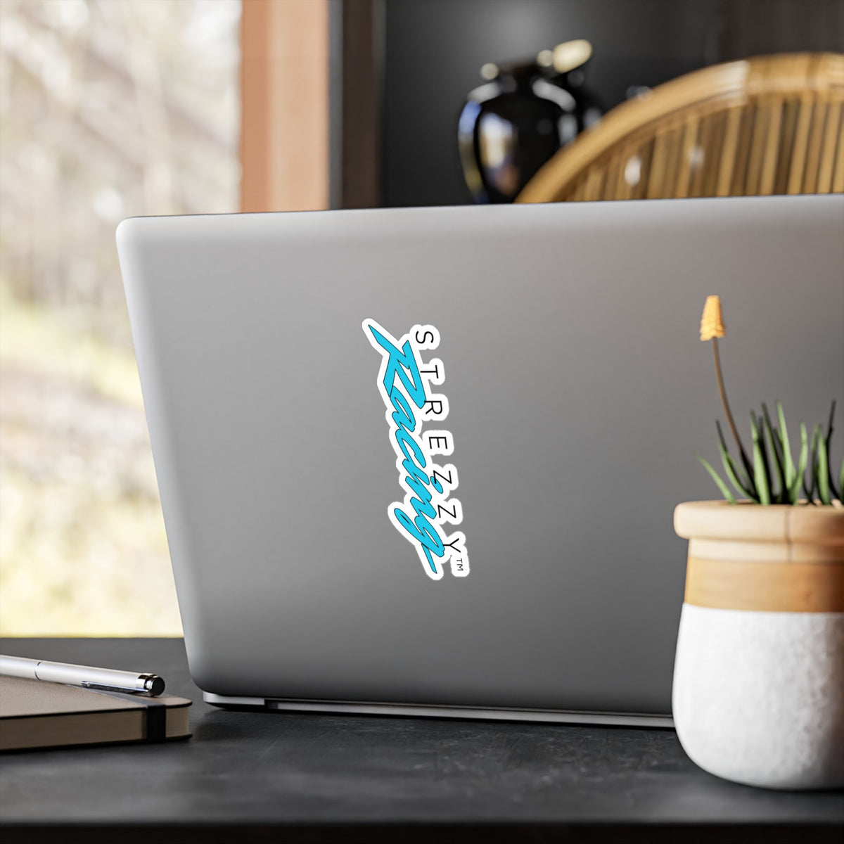 Kiss-cut racing logo sticker on laptop lid, teal “Kaching” script with white border