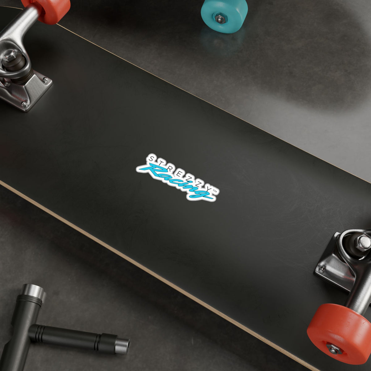 Kiss-cut racing logo sticker on skateboard deck, teal “Kaching” script