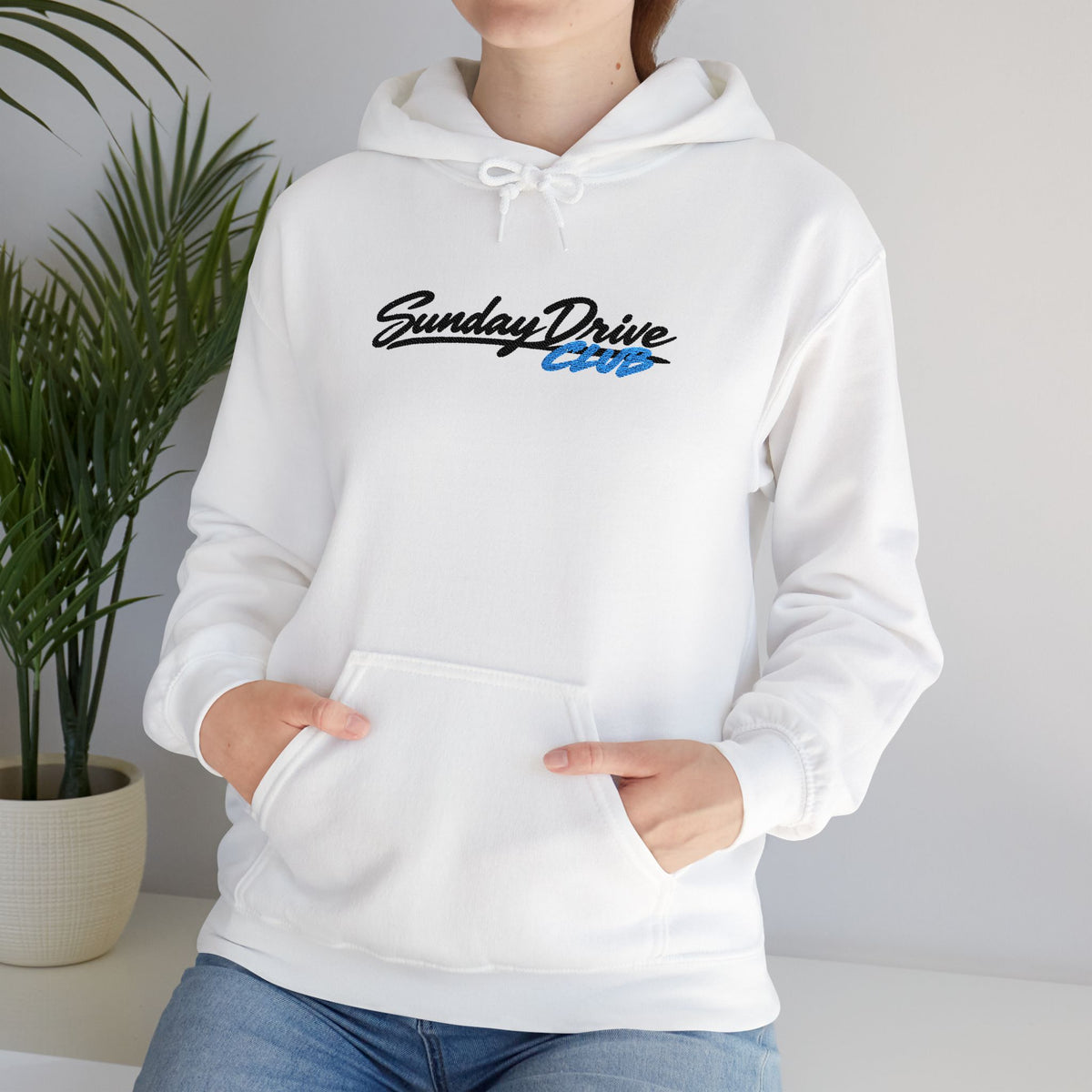 White hoodie on model showing embroidered chest logo and drawstring hood.